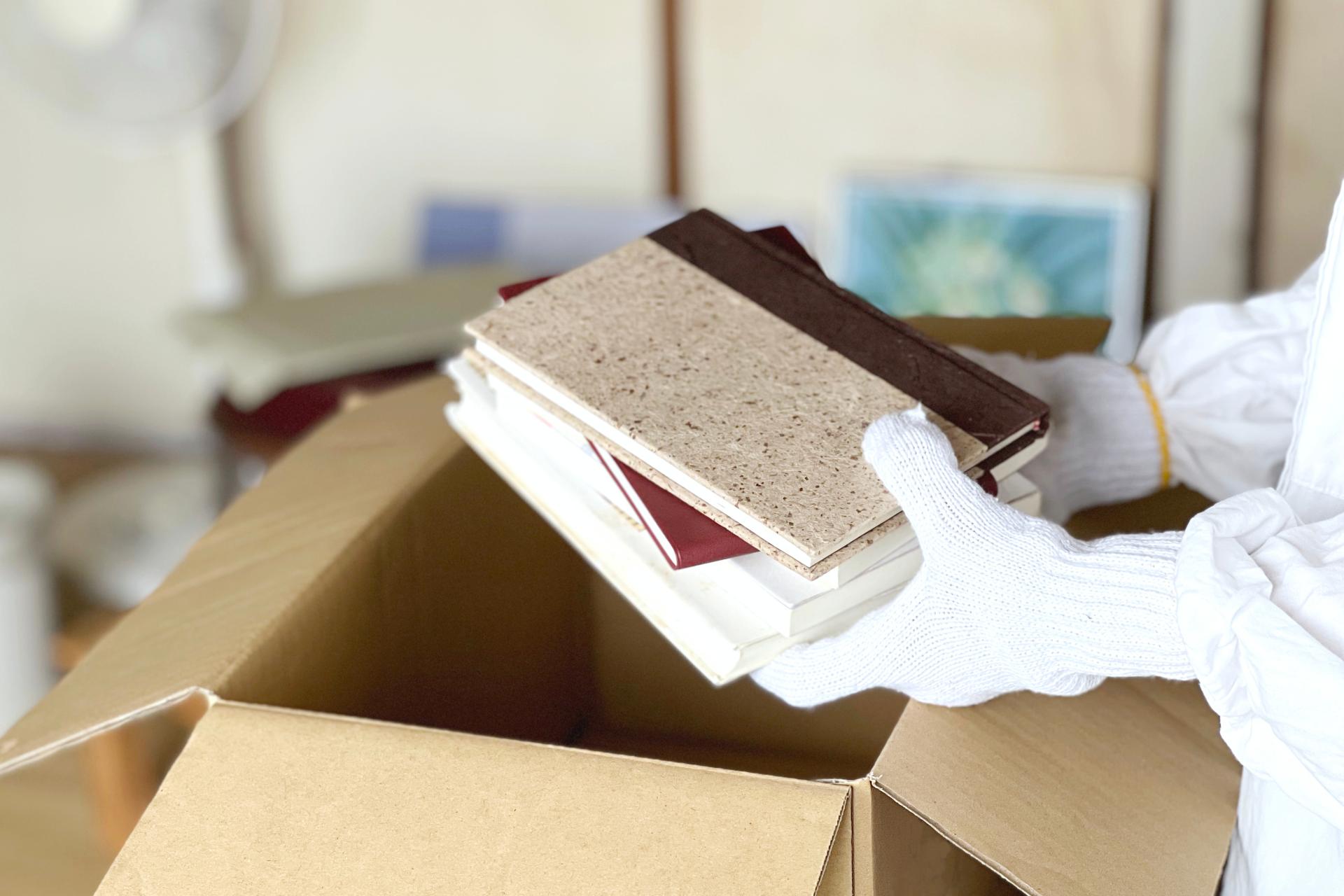 遺品を一冊ずつ丁寧に確認しながら仕分けする遺品整理の作業風景