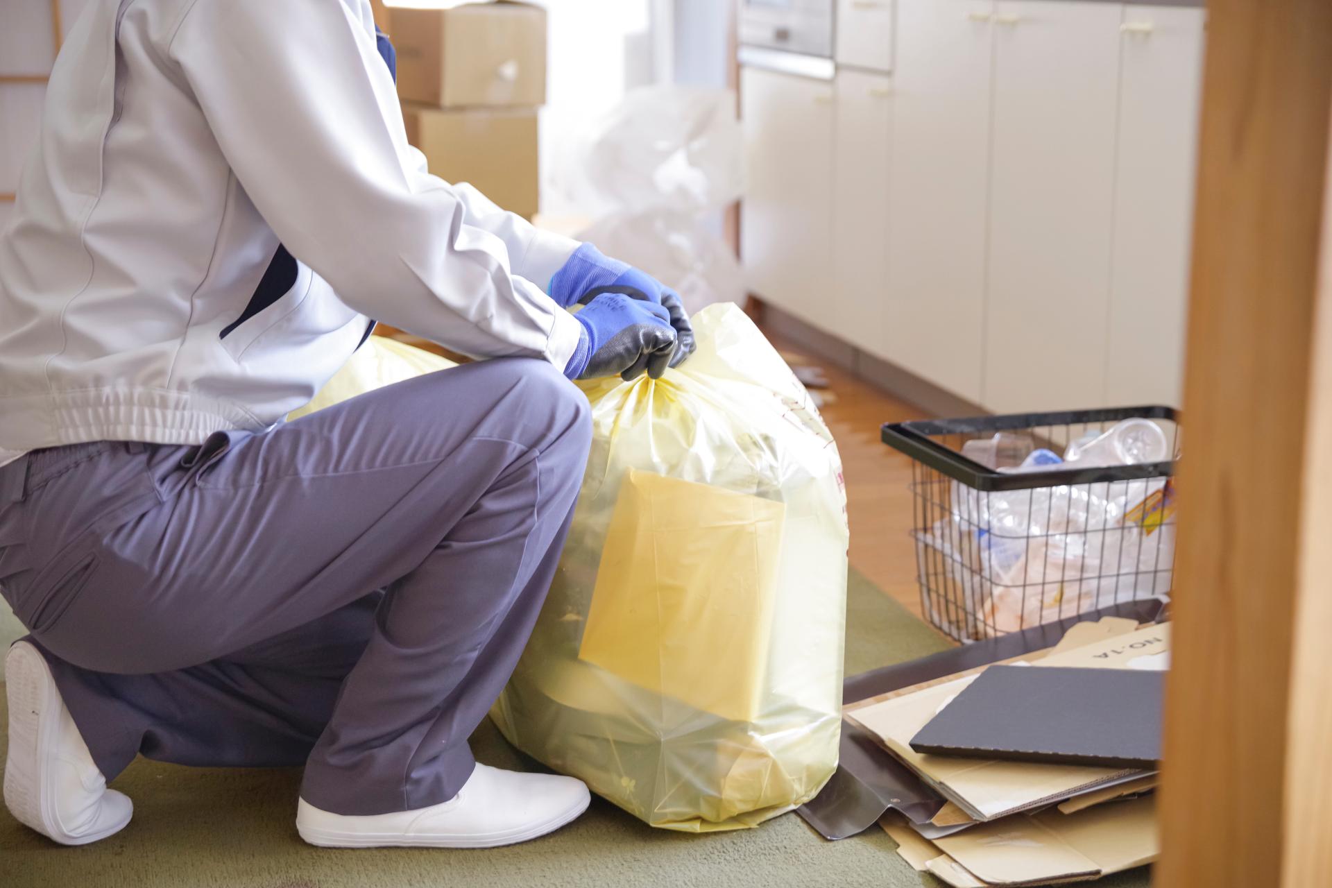 手袋と作業着を着用したスタッフが不用品を安全に袋詰めしている様子